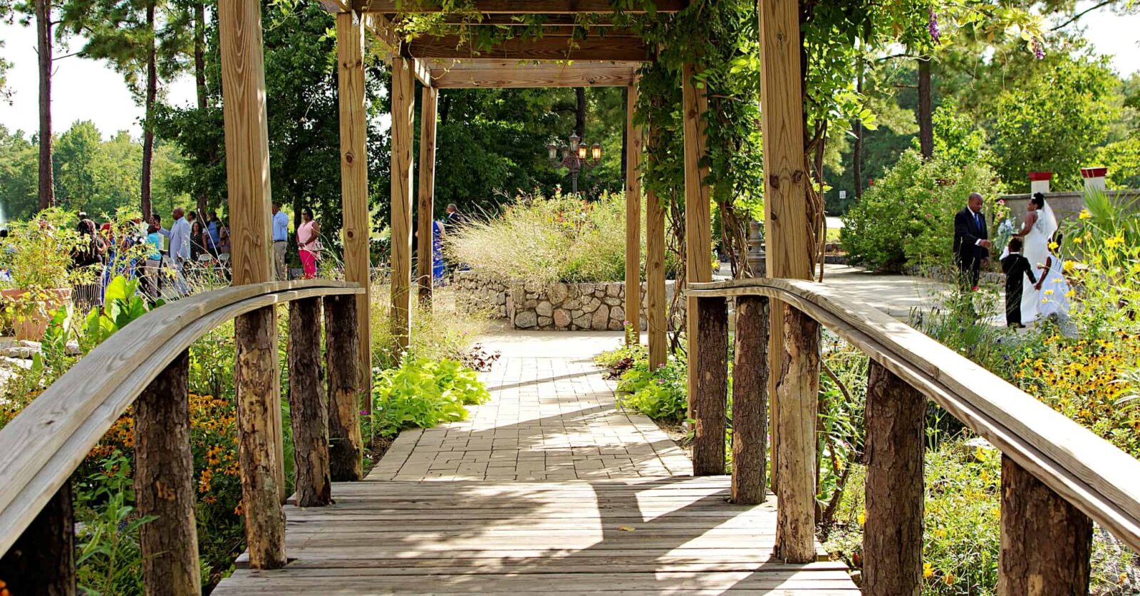 A wooden walkway with an arbor and bench.