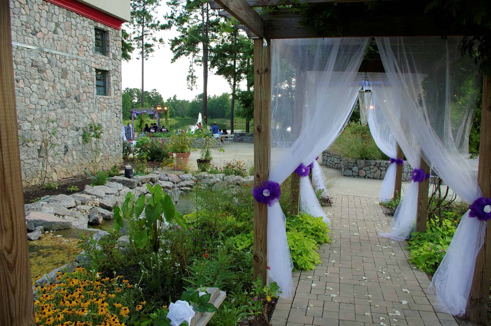 A wedding venue with purple flowers and white curtains.