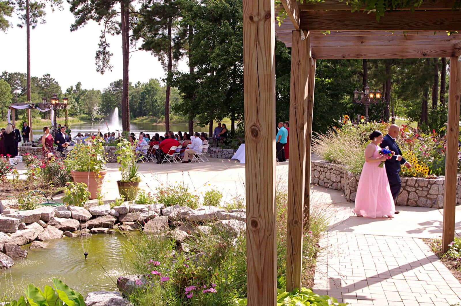 A couple in pink dress standing next to pond.