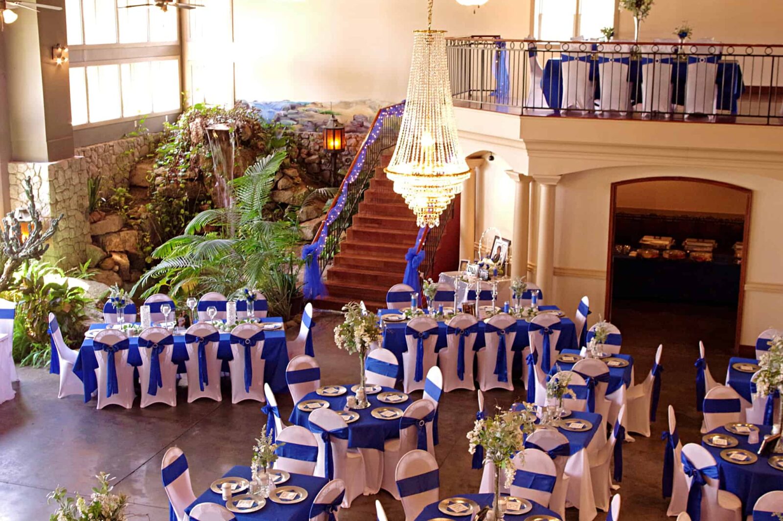 A room filled with tables and chairs covered in blue and white linens.